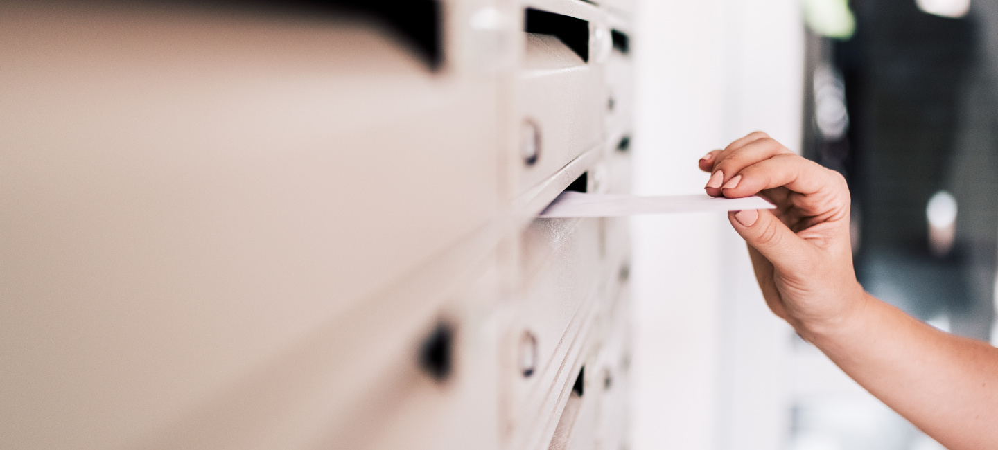 Pessoa a colocar correio publicitário numa caixa de correio