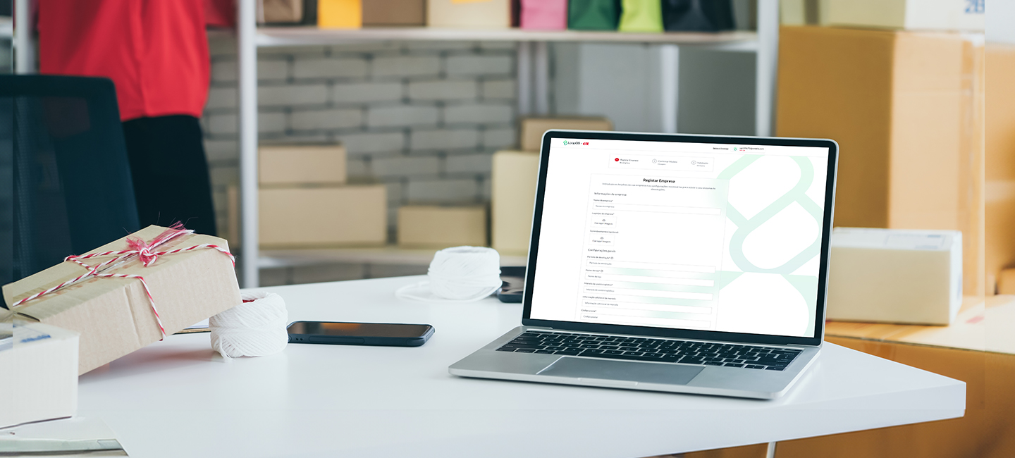 Computador ligado, com uma encomenda em cima da mesa.