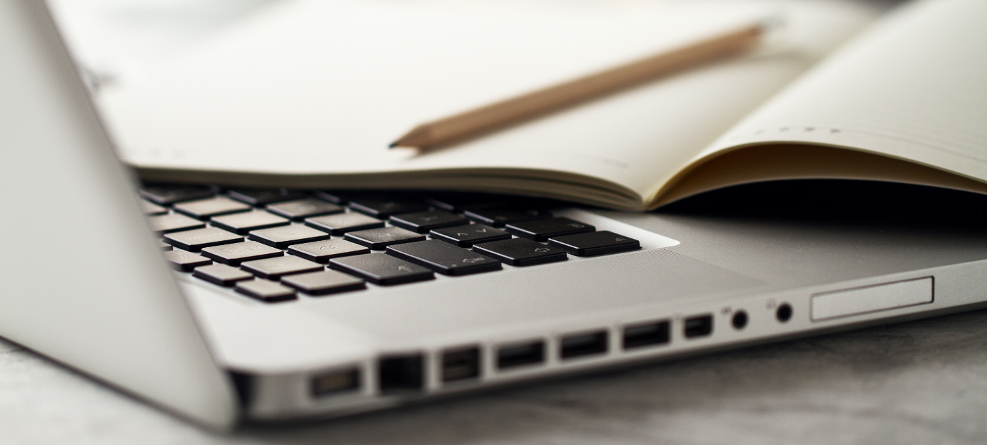 Computador com um caderno aberto em cima do seu teclado