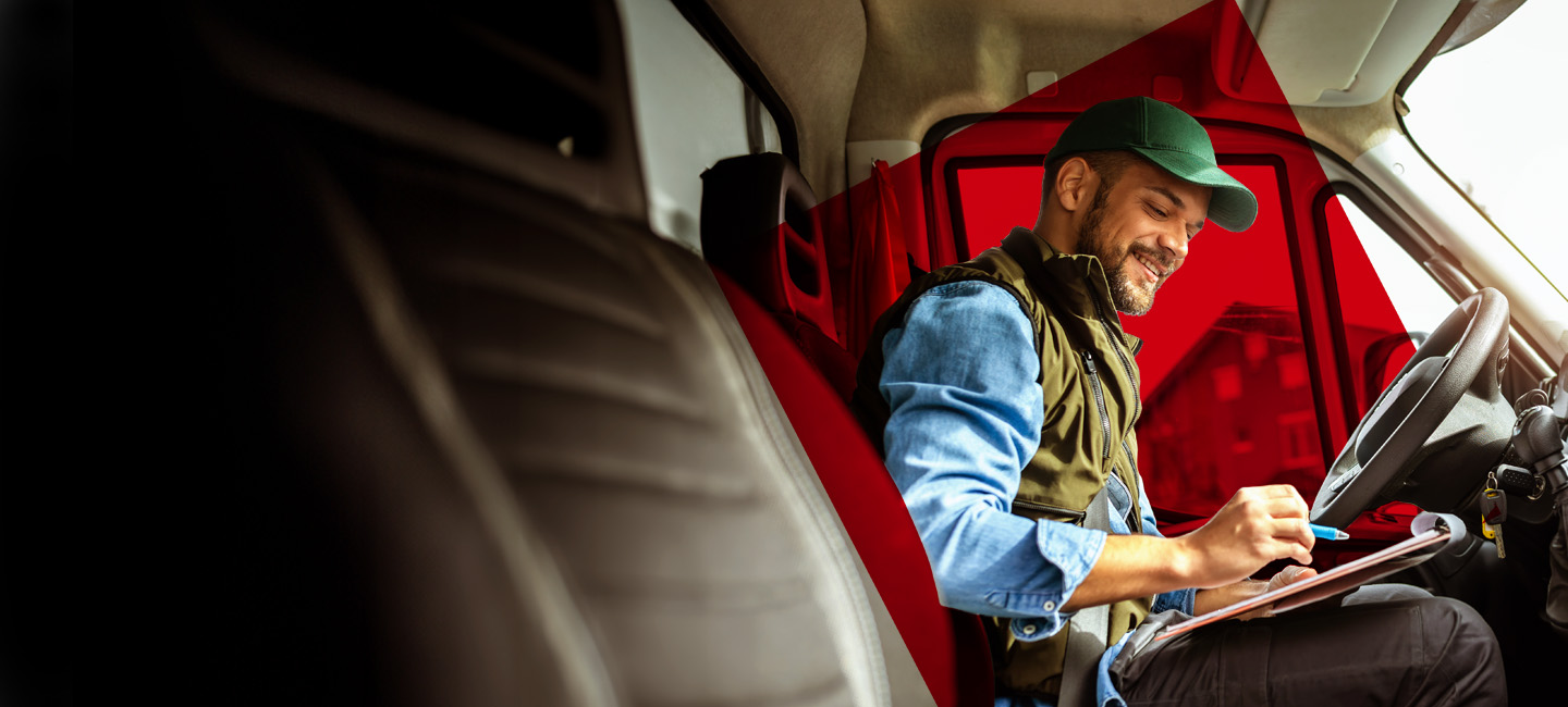 Homem sentado no seu automóvel a preencher o Seguro Auto Empresas.