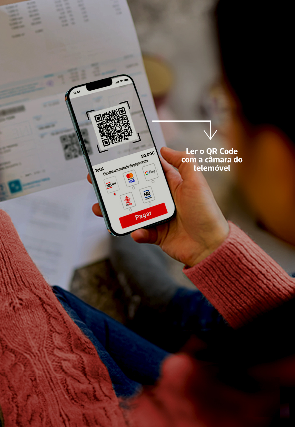 Pessoa segura uma fatura e um telemóvel com QR Code visível para pagamento digital.