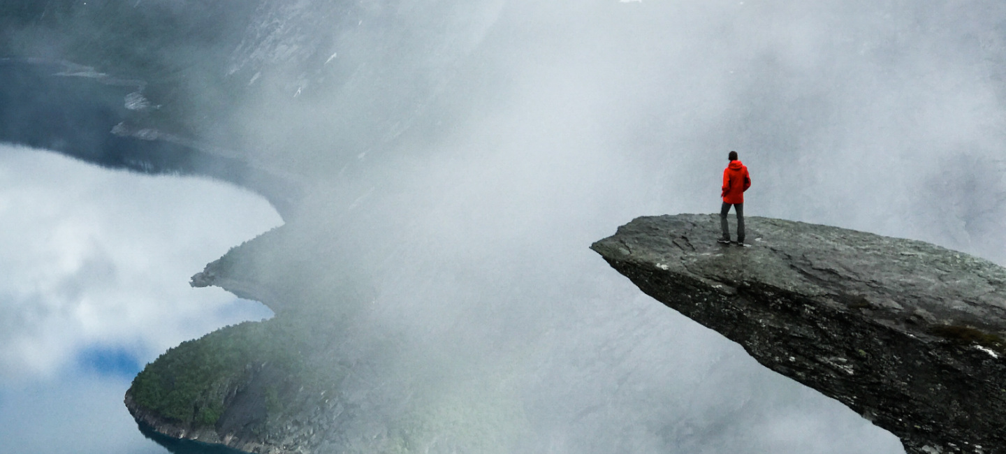 Pessoa em cima de uma rocha bastante alta.