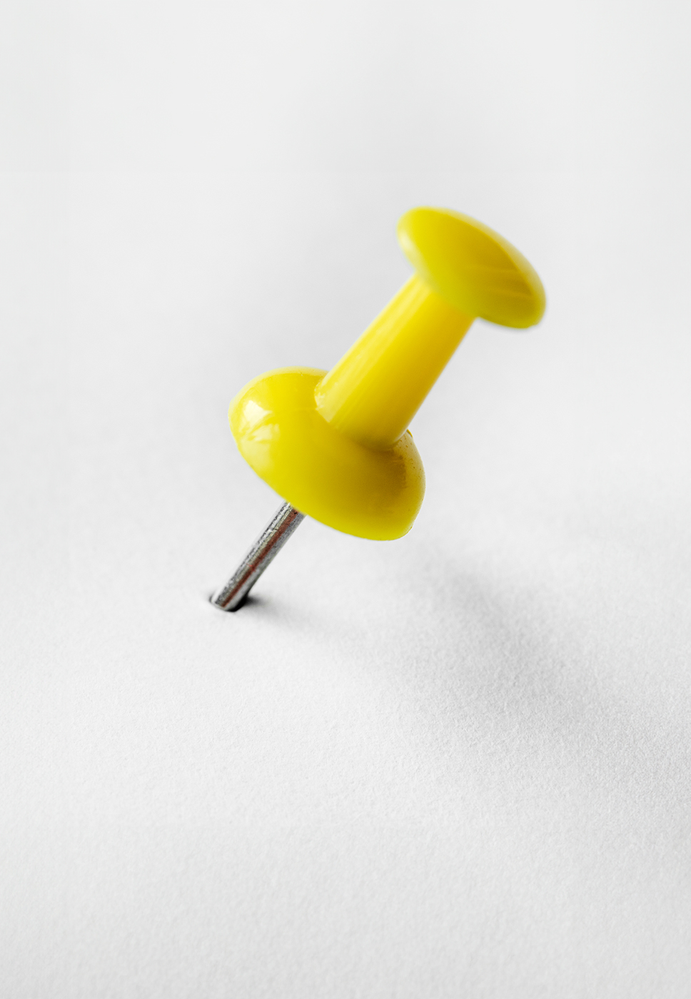 Alfinete de quadros espetado numa folha branca