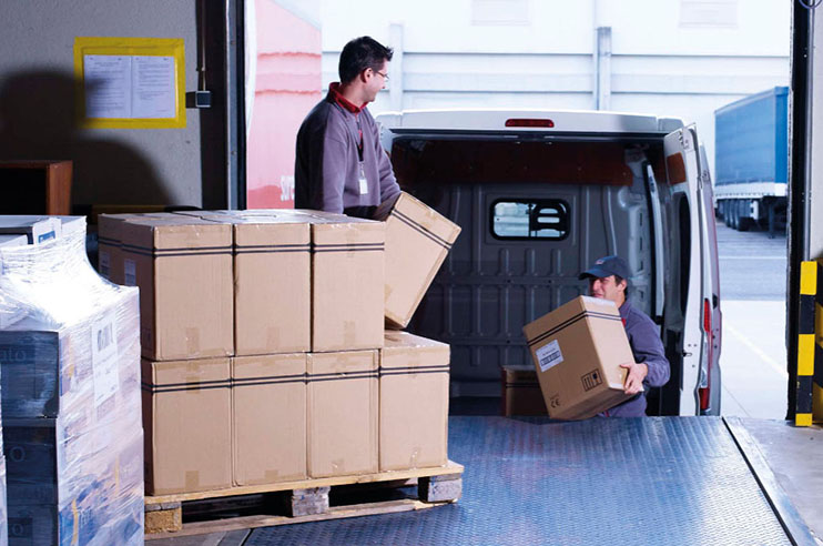 Trabalhadores a carregarem a carrinha com encomendas.